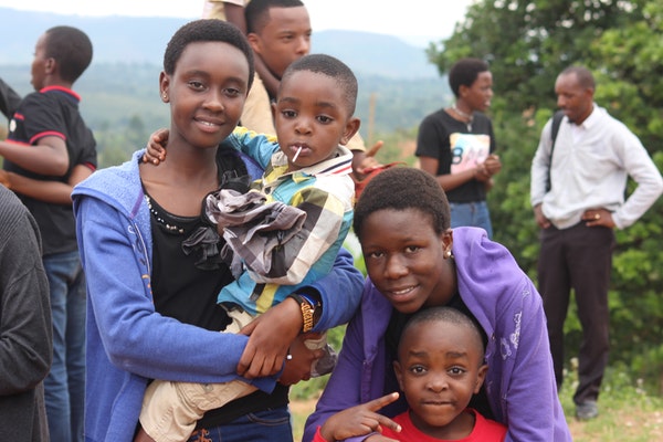 African woman wearing blue jacket carrying a little boy