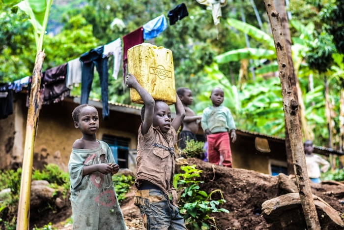 African little boy carrying container of water over his head