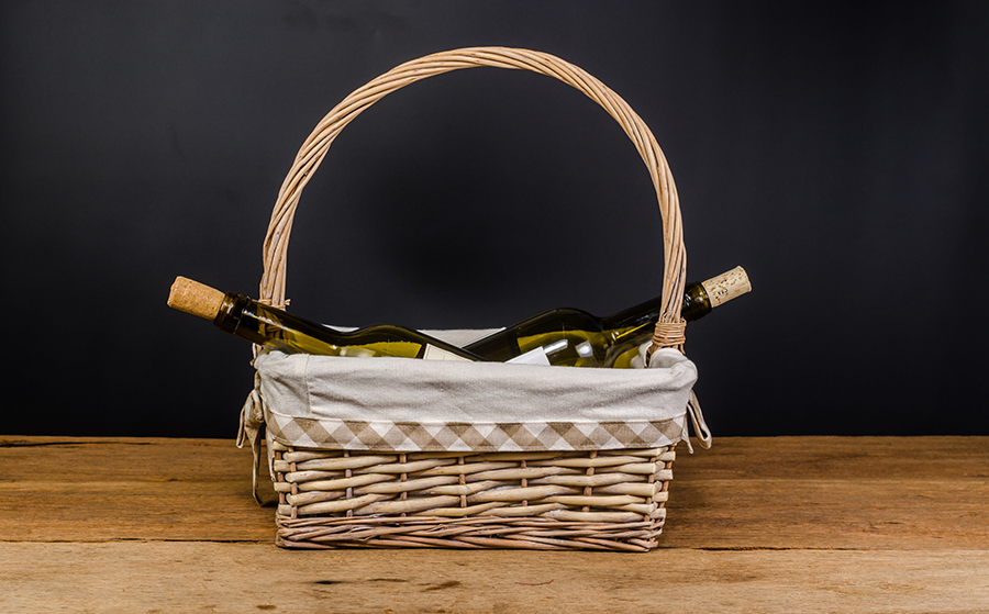 red wine bottles on wicker basket on wooden board and black background