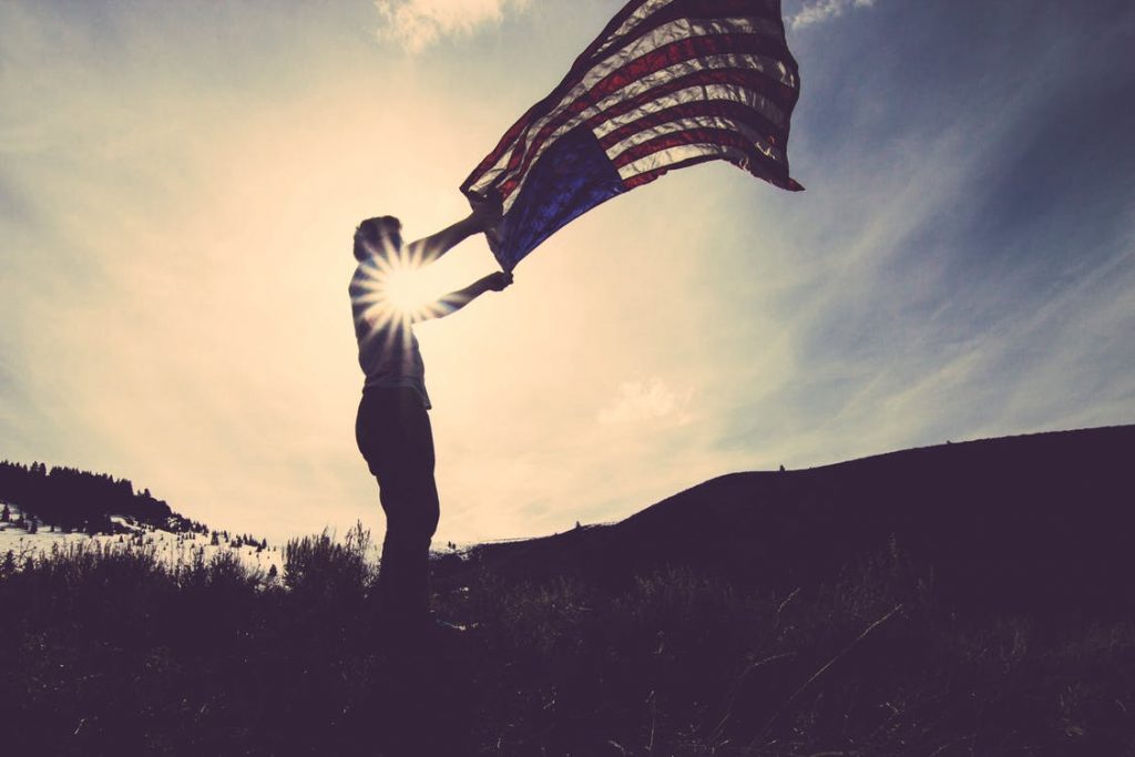veteran in a sunset raising America Flag